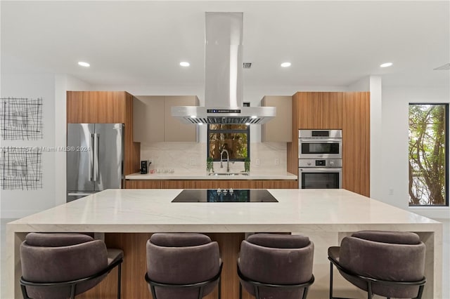 kitchen featuring sink, stainless steel appliances, tasteful backsplash, a kitchen breakfast bar, and island range hood