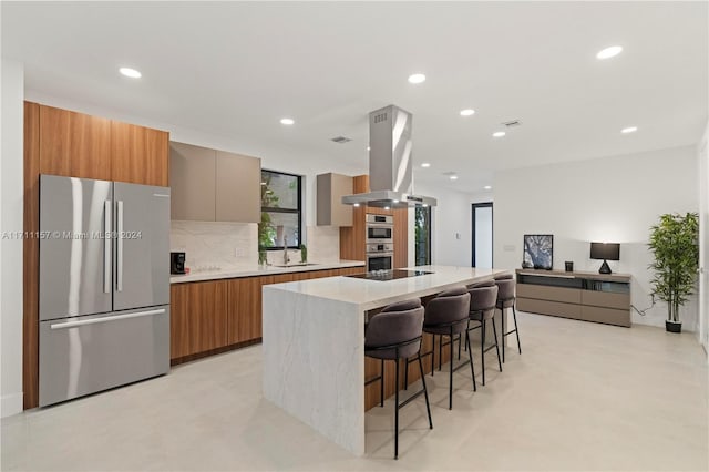 kitchen featuring tasteful backsplash, island exhaust hood, a breakfast bar area, a kitchen island, and appliances with stainless steel finishes