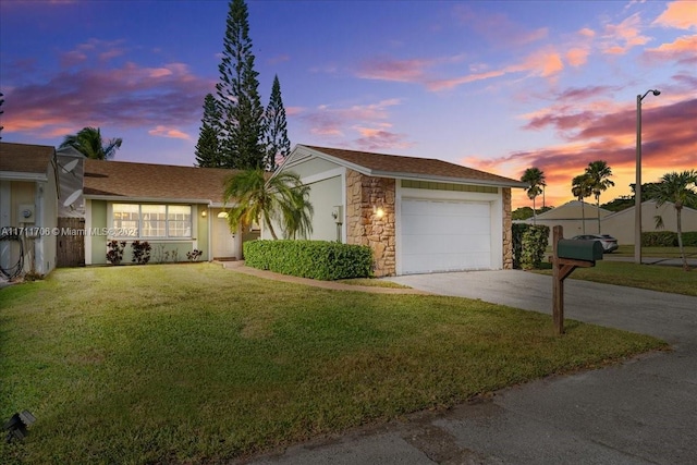 single story home featuring a garage and a lawn