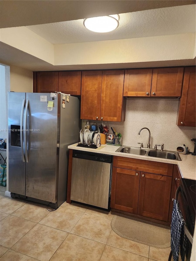 kitchen featuring light tile patterned floors, sink, a textured ceiling, and appliances with stainless steel finishes