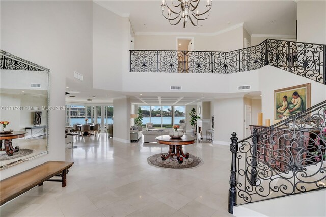 tiled entryway featuring a chandelier, crown molding, and a towering ceiling