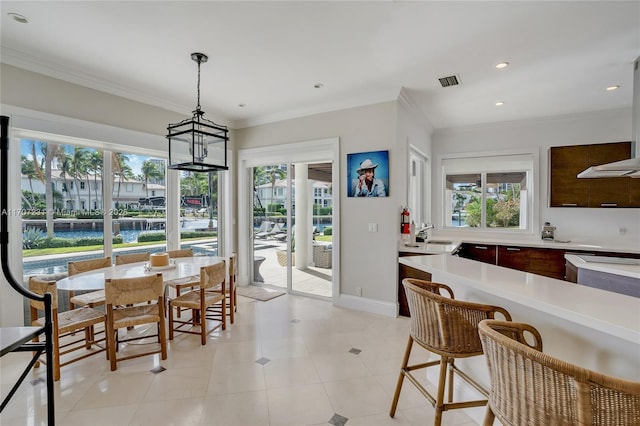 tiled dining room featuring crown molding and a water view