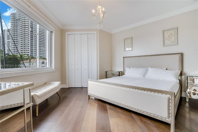 bedroom with an inviting chandelier, crown molding, wood-type flooring, and a closet