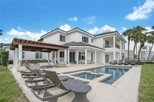 back of house featuring a swimming pool with hot tub, a pergola, outdoor lounge area, a patio, and a balcony