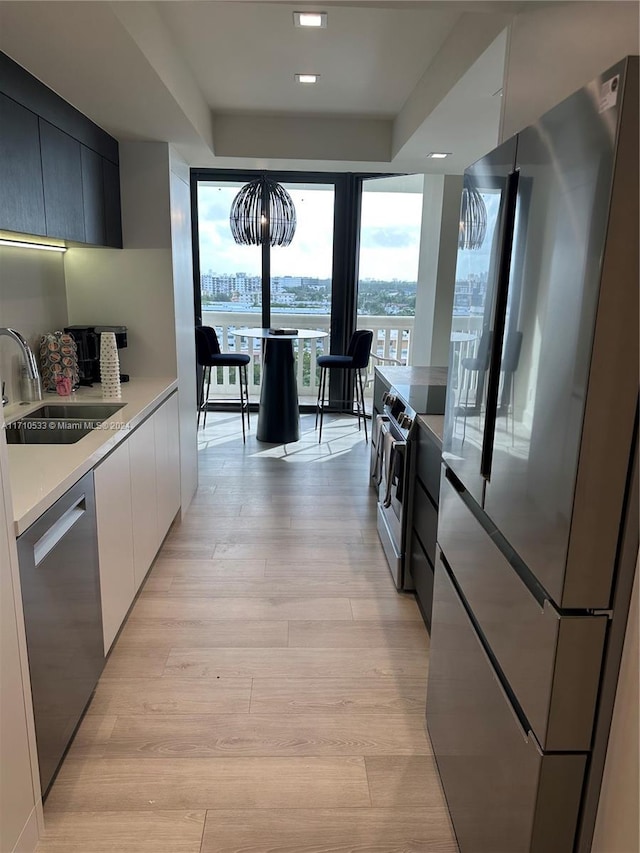 kitchen with white cabinets, appliances with stainless steel finishes, light wood-type flooring, and sink