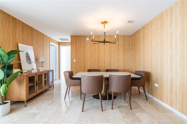 dining area featuring wood walls and a chandelier