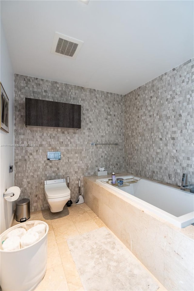 bathroom with tile patterned flooring, tiled tub, a bidet, toilet, and tile walls