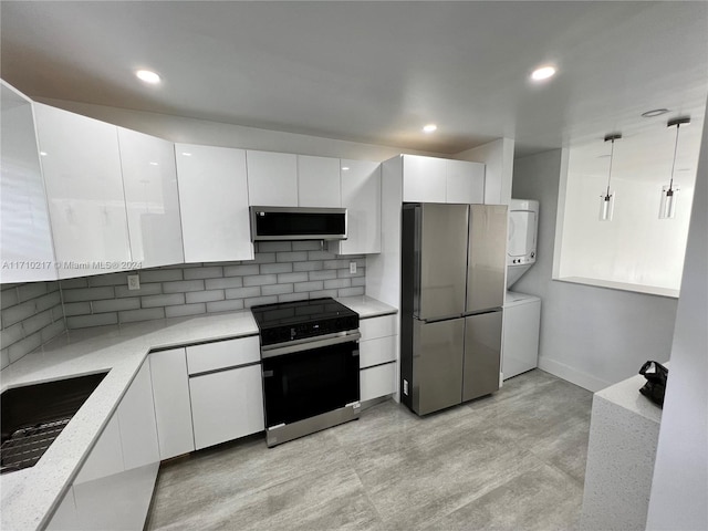 kitchen featuring white cabinets, sink, hanging light fixtures, appliances with stainless steel finishes, and stacked washer / dryer