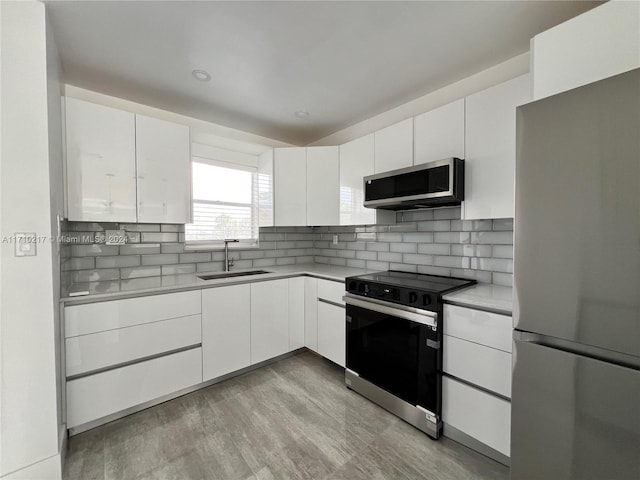 kitchen featuring white cabinetry, sink, stainless steel appliances, and light hardwood / wood-style flooring