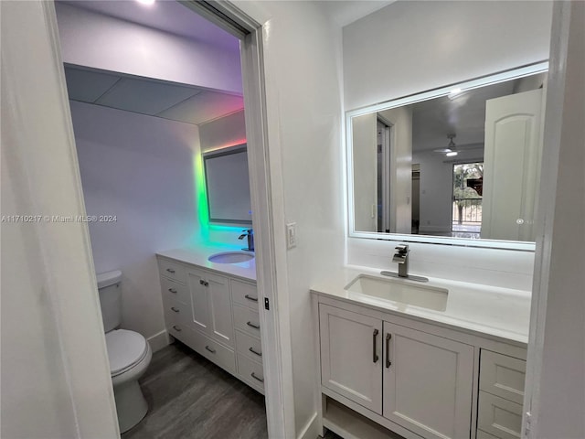 bathroom with ceiling fan, toilet, wood-type flooring, and vanity