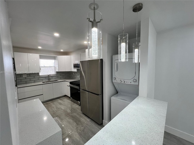 kitchen with sink, stainless steel appliances, decorative light fixtures, white cabinets, and stacked washer and clothes dryer