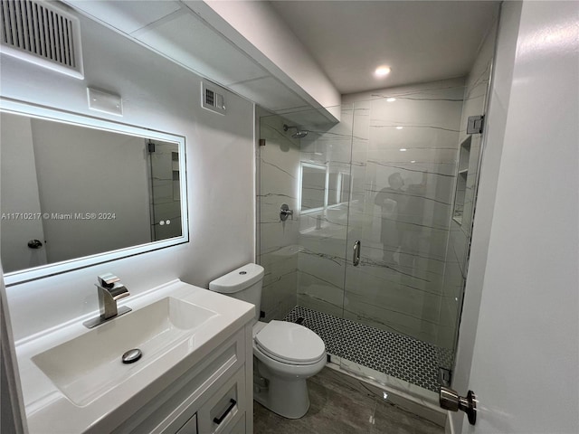 bathroom featuring vanity, toilet, and a shower with door