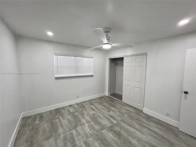 unfurnished bedroom featuring hardwood / wood-style flooring, ceiling fan, and a closet