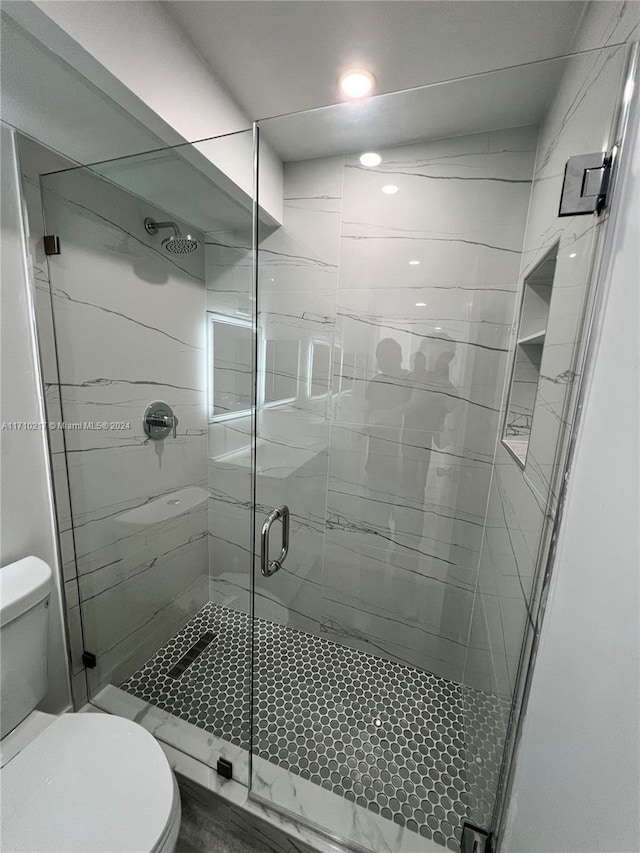 bathroom with toilet and a shower with door