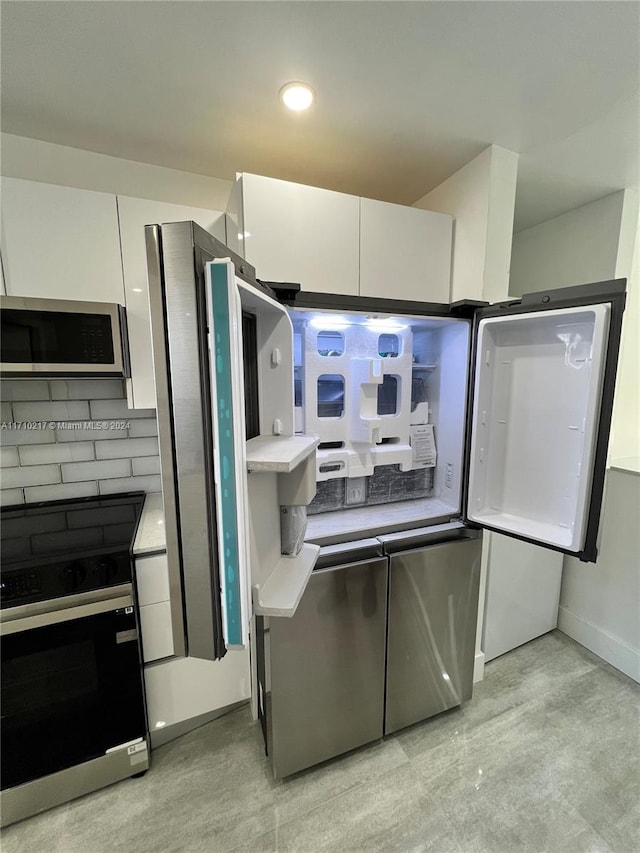 kitchen with white cabinets, decorative backsplash, and stainless steel appliances