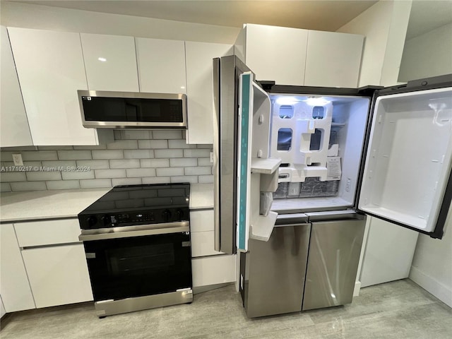 kitchen with tasteful backsplash, white cabinets, and appliances with stainless steel finishes