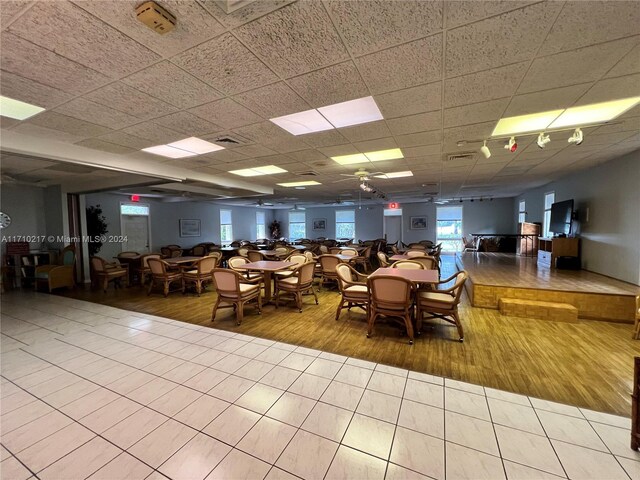 dining area with a paneled ceiling, ceiling fan, and light wood-type flooring