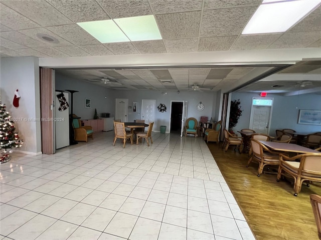 dining room featuring light wood-type flooring, a drop ceiling, and ceiling fan