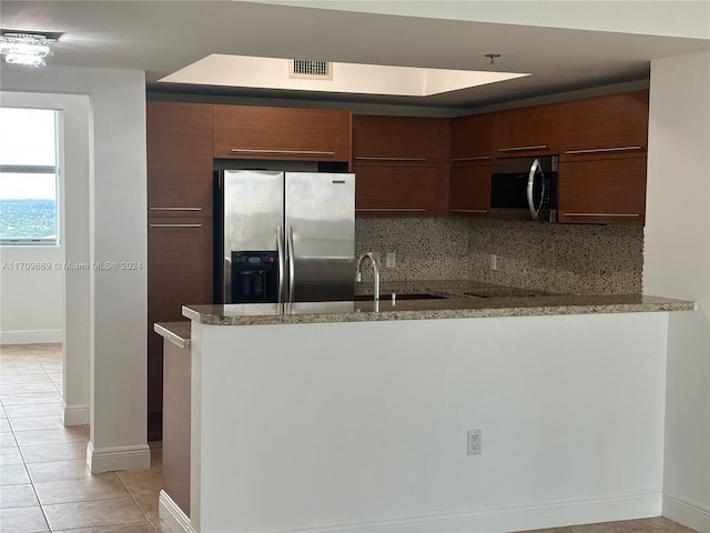 kitchen featuring light stone countertops, light tile patterned floors, backsplash, and stainless steel appliances