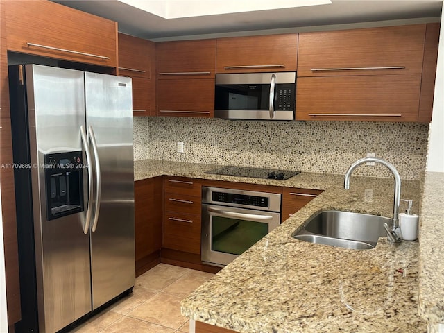 kitchen with sink, light stone counters, decorative backsplash, light tile patterned flooring, and appliances with stainless steel finishes