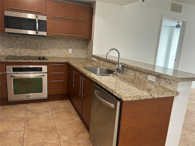 kitchen featuring sink, decorative backsplash, light stone countertops, kitchen peninsula, and stainless steel appliances