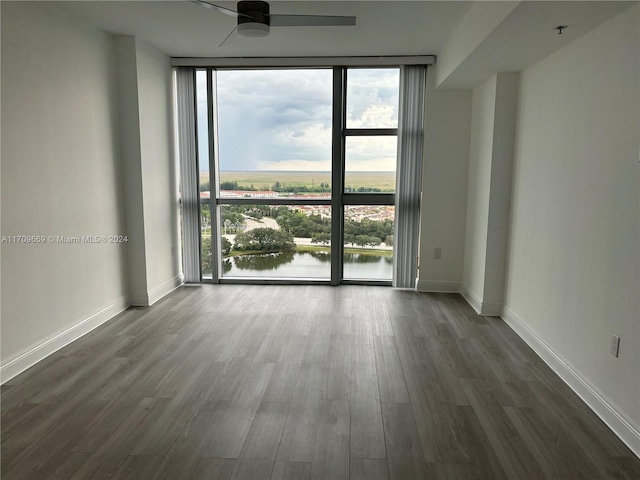 spare room featuring hardwood / wood-style floors, ceiling fan, expansive windows, and a water view