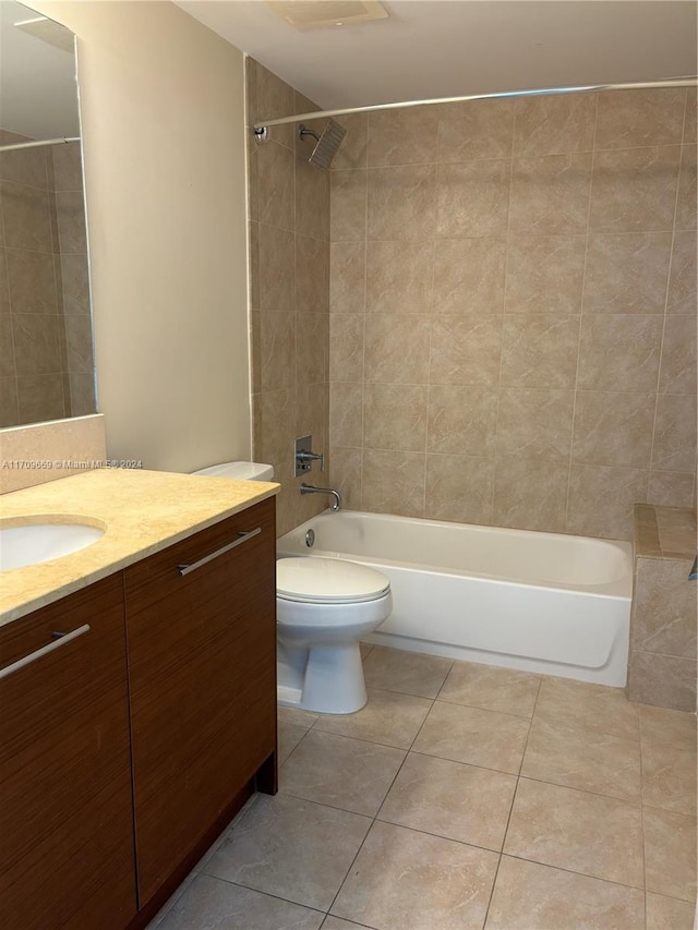 full bathroom with tile patterned flooring, vanity, tiled shower / bath combo, and toilet