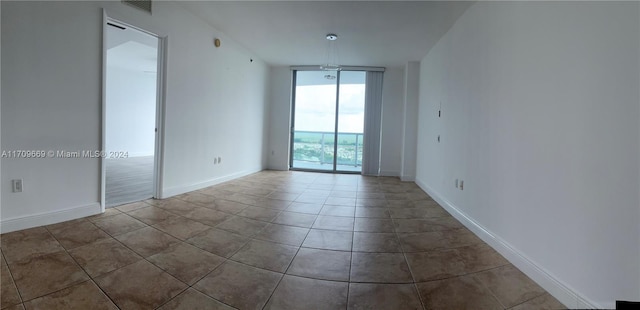 spare room with light tile patterned floors and floor to ceiling windows