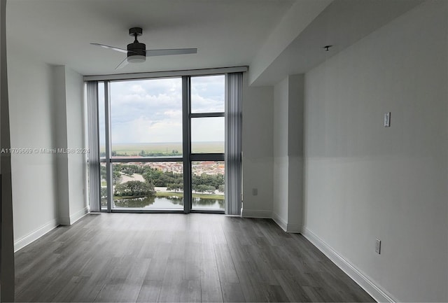 unfurnished room featuring ceiling fan, a water view, a wealth of natural light, and dark hardwood / wood-style floors