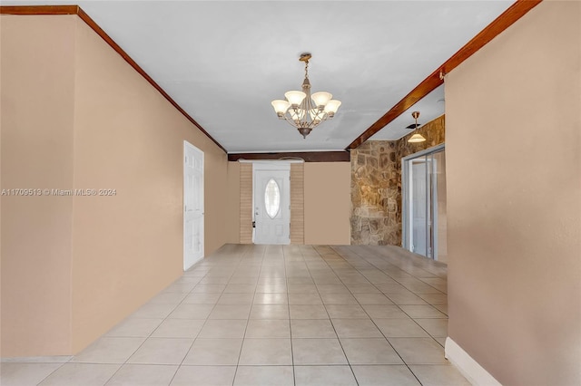 foyer entrance with light tile patterned floors, crown molding, and a notable chandelier