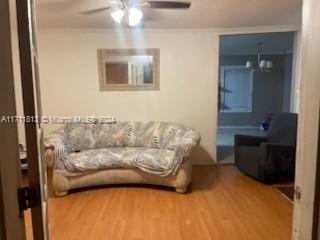 living room with hardwood / wood-style floors, ceiling fan, and crown molding