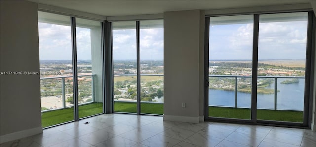 spare room featuring floor to ceiling windows, a water view, and plenty of natural light