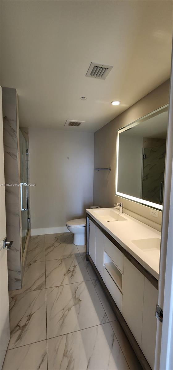 bathroom with vanity, toilet, and a shower with door