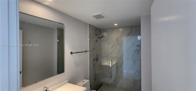 bathroom with tiled shower, vanity, and toilet