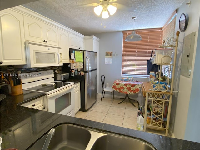 kitchen featuring a textured ceiling, light tile patterned floors, decorative light fixtures, and white appliances