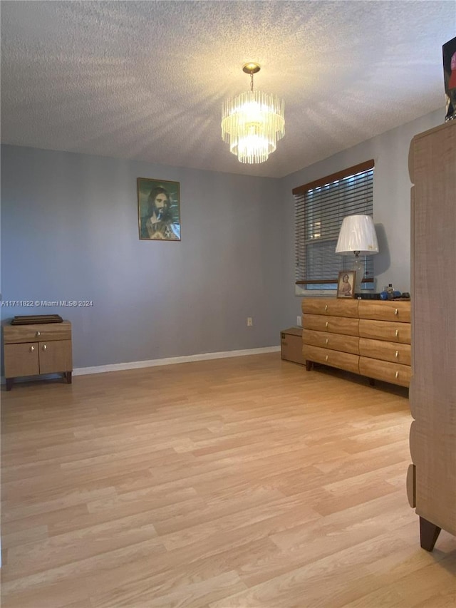 bedroom with wood-type flooring, a textured ceiling, and an inviting chandelier