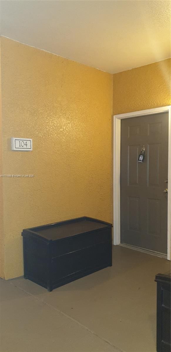 foyer featuring concrete flooring and a textured wall