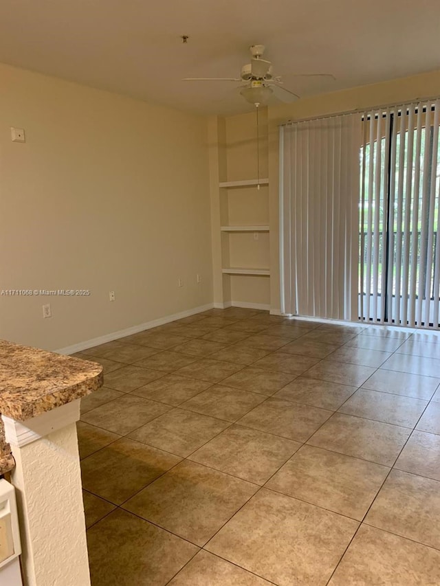 unfurnished room featuring a ceiling fan, light tile patterned flooring, and baseboards