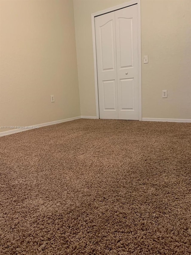 unfurnished bedroom with carpet floors, a closet, and baseboards