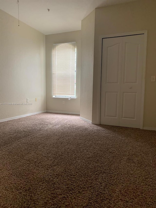 carpeted empty room with baseboards