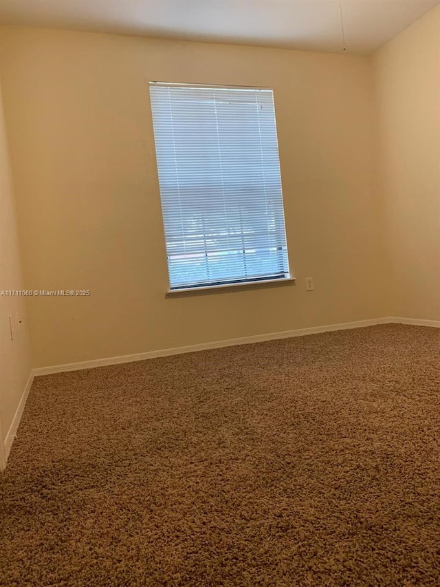 carpeted spare room featuring baseboards