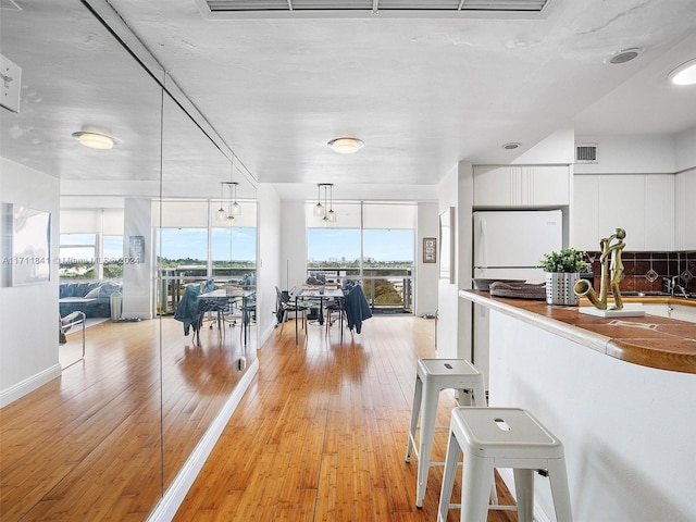 kitchen featuring hanging light fixtures, light hardwood / wood-style floors, white fridge, and white cabinetry