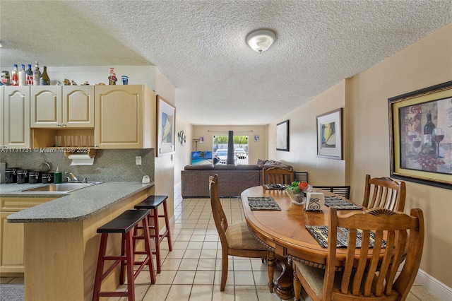 dining space with a textured ceiling, light tile patterned floors, and sink