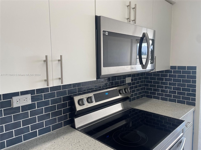 kitchen with white cabinets, light stone counters, and stainless steel appliances