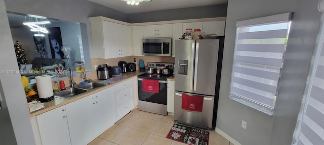 kitchen featuring an inviting chandelier, white cabinets, sink, light tile patterned floors, and appliances with stainless steel finishes