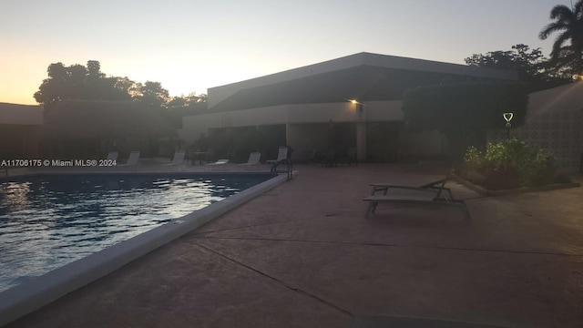 pool at dusk featuring a patio area