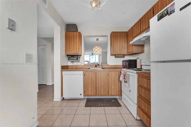 kitchen featuring light tile patterned flooring, a textured ceiling, white appliances, and sink