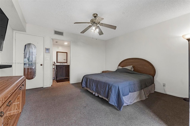 bedroom with dark colored carpet, a textured ceiling, ensuite bath, and ceiling fan