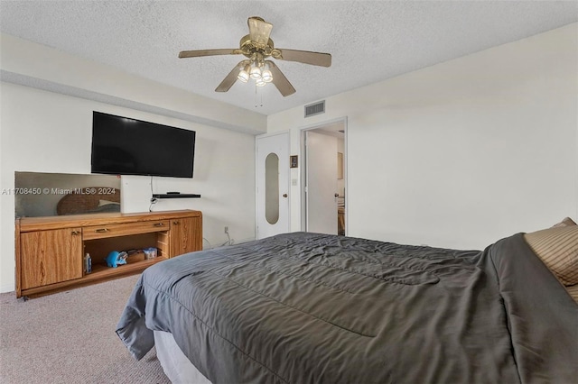 bedroom featuring ceiling fan, light colored carpet, and a textured ceiling