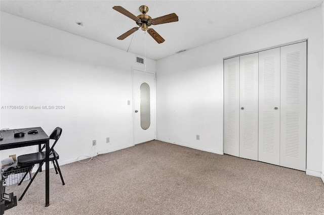 unfurnished office featuring ceiling fan, light colored carpet, and a textured ceiling